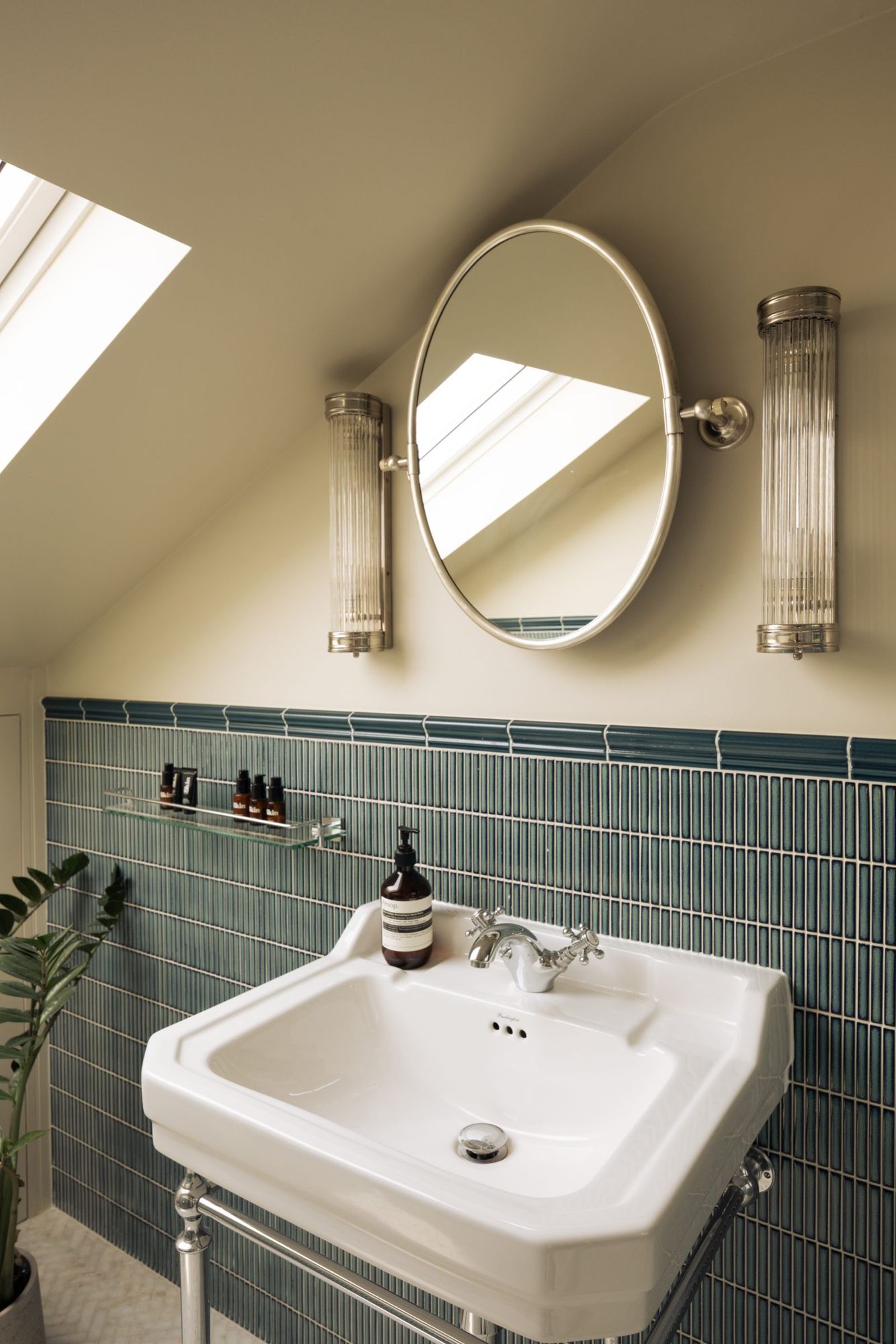 Loft bathroom basin with green tiles and oval mirror