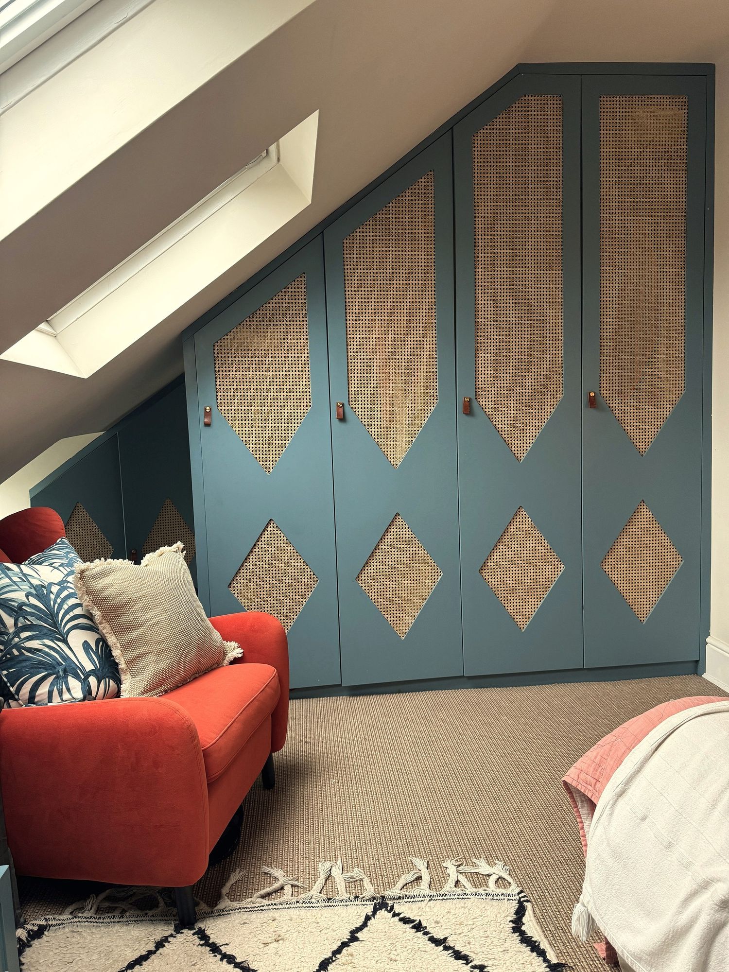 Primary bedroom eaves wardrobes in blue with cane panels and leather pulls